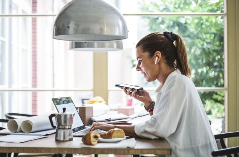 Woman using a smartphone at a home office desk
