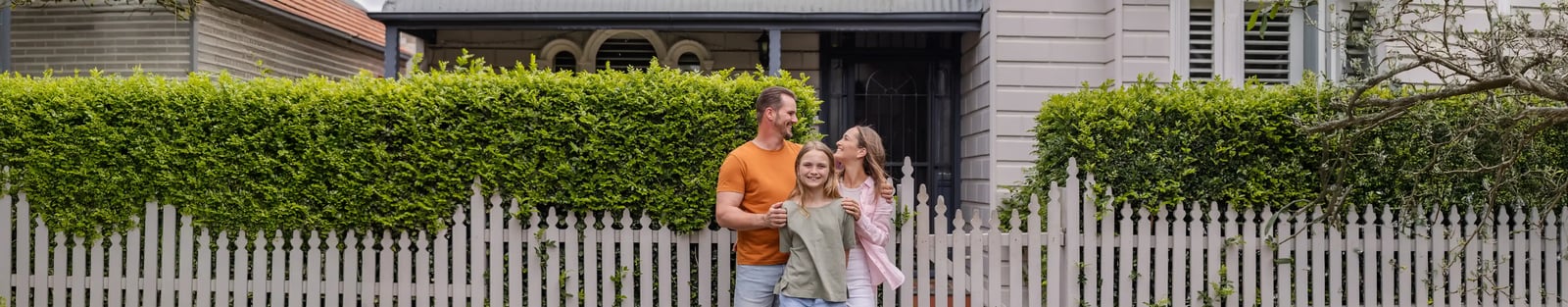 Family smiling in front of house